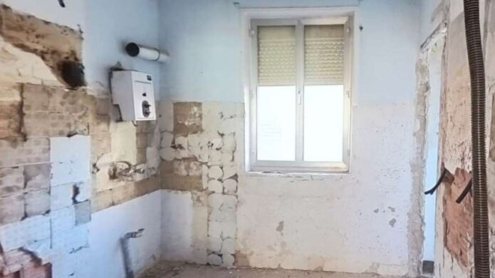 Cocina en estado deficiente con paredes dañadas y sin mobiliario