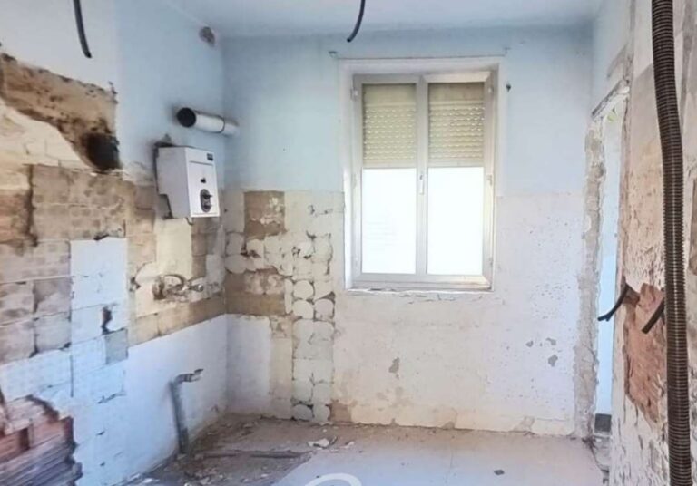 Cocina en estado deficiente con paredes dañadas y sin mobiliario