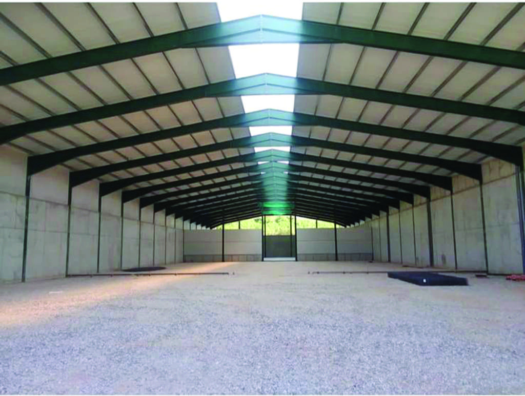 Interior de una nave industrial con estructura metálica y suelo de grava