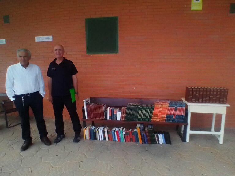 Dos hombres junto a una mesa con libros donados en una prisión.