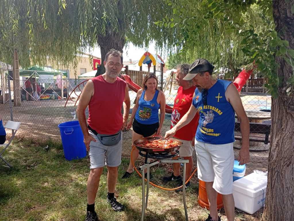Grupo de personas cocinando en una barbacoa durante la fiesta asturiana.