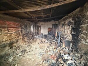 Interior de una finca quemada en El Hoyo, Palencia, con escombros y cenizas.
