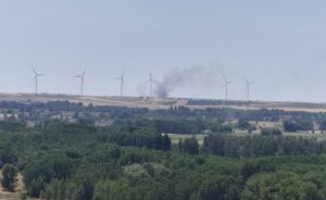 Vista de un incendio forestal en Palencia con humo y molinos de viento