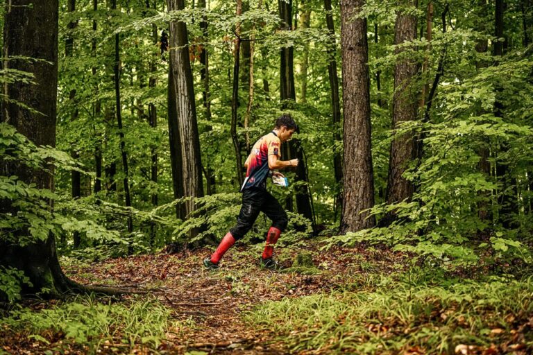 Joven orientador corriendo en un bosque durante una competición de orientación