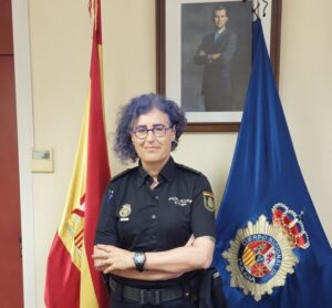 Mujer policía en oficina con banderas de España y Policía Nacional