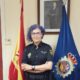 Mujer policía en oficina con banderas de España y Policía Nacional