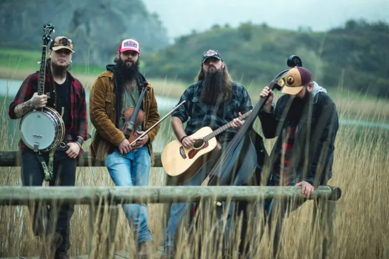 Banda Moonshine Wagon en un entorno natural con instrumentos musicales.