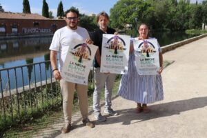 Tres personas sosteniendo carteles de La Noche Blanca en Palencia junto al agua