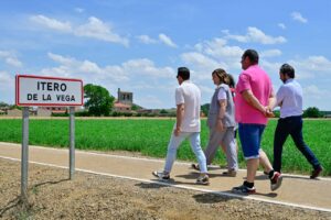 Grupo de personas caminando junto a un cartel de Itero de la Vega en el Camino de Santiago.