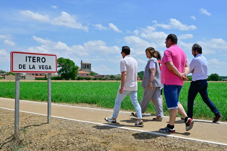 Grupo de personas caminando junto a un cartel de Itero de la Vega en el Camino de Santiago.