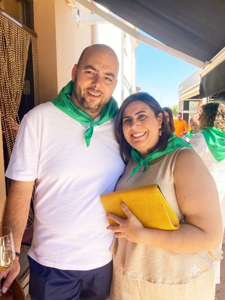 Pareja sonriente en la Panadería Berruguete con pañuelos verdes
