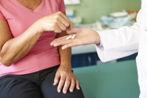Mujer recibiendo pastillas de un médico en consulta.
