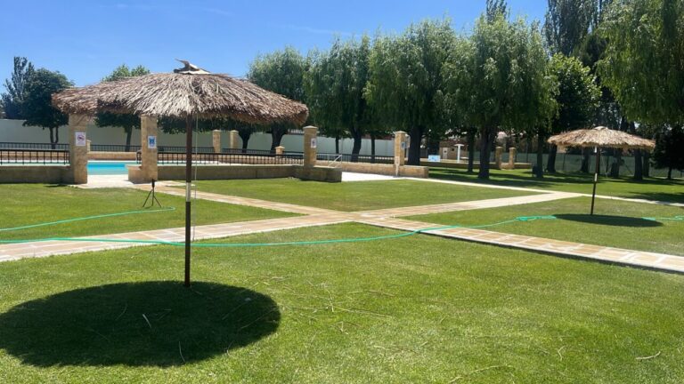 Vista de las piscinas de Paredes de Nava con sombrillas y césped