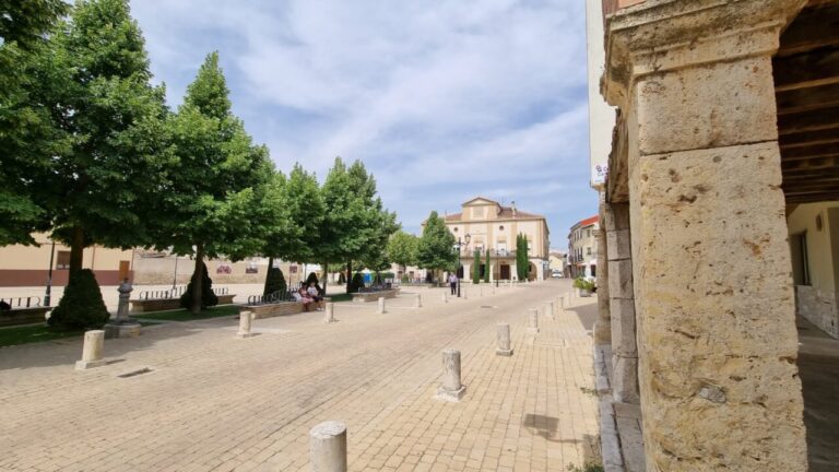 Vista de la plaza en Dueñas con árboles y un edificio al fondo
