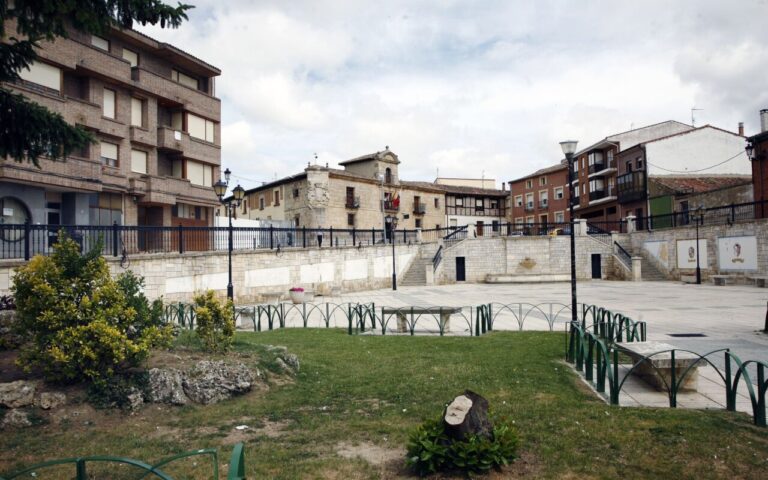 Vista de la plaza en Osorno, Palencia con edificios y vegetación