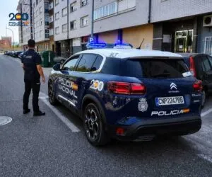 Agente de la Policía Nacional junto a un coche patrulla en la calle