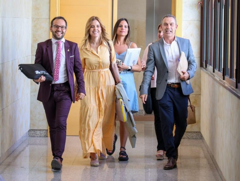 Procuradores del PSOE caminando en un pasillo con documentos.