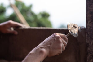 Mano aplicando yeso en una pared durante la renovación de una vivienda.