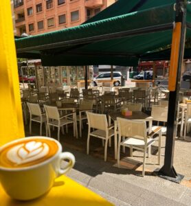 Taza de café en una terraza con mesas vacías en Palencia