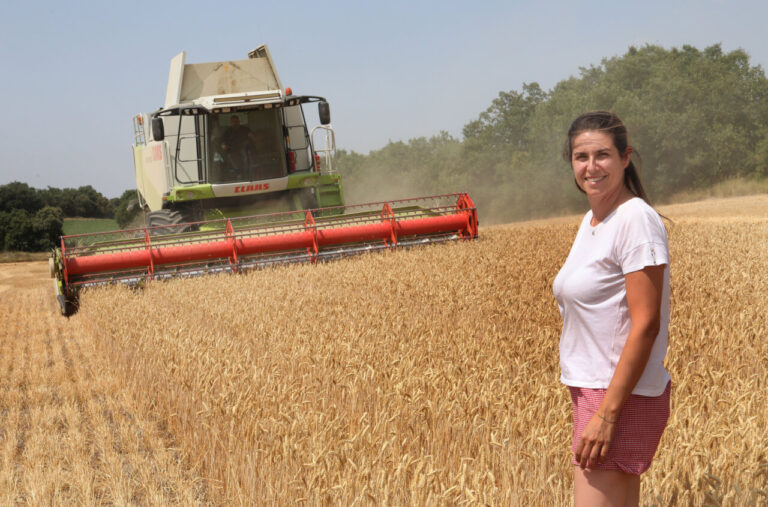 Mujer junto a cosechadora en campo de trigo en Palencia