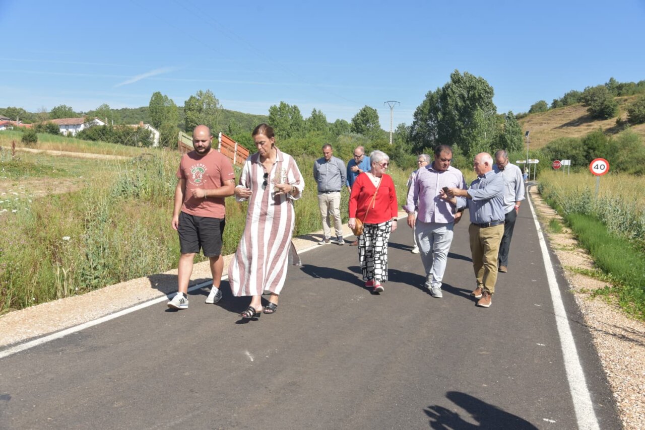 Grupo de personas caminando por una carretera recién asfaltada en La Puebla de Valdavia