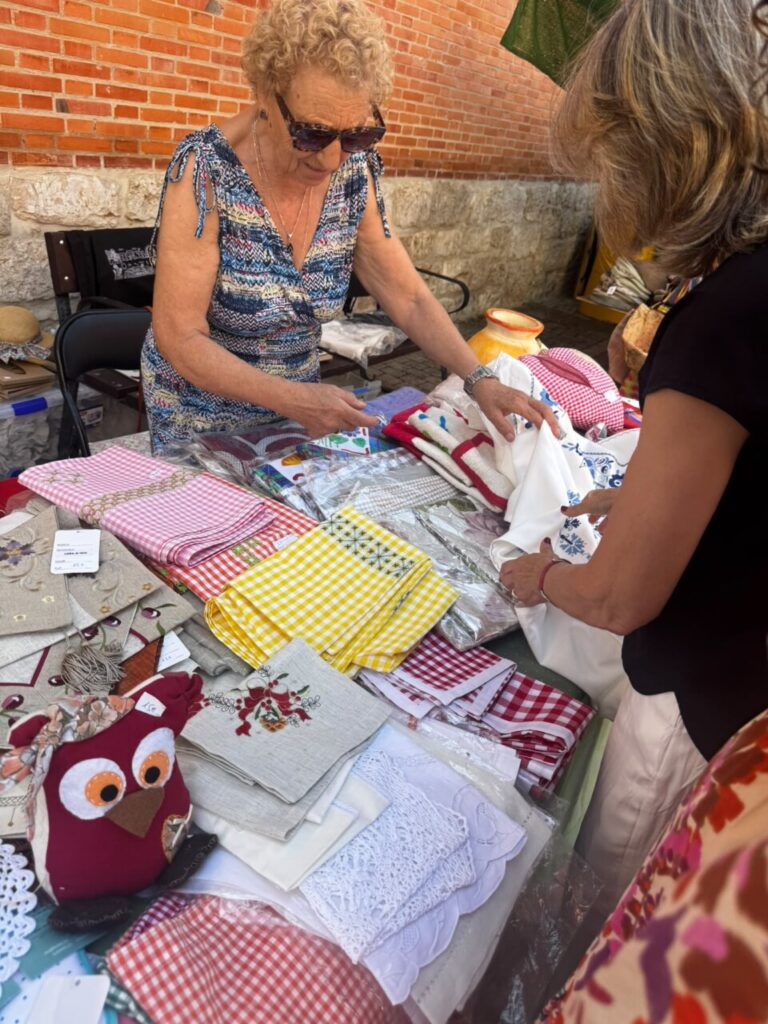 Mujeres comprando productos artesanales en una feria en Baltanás