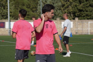 Jugadores en entrenamiento de fútbol con camisetas rosas en el campo