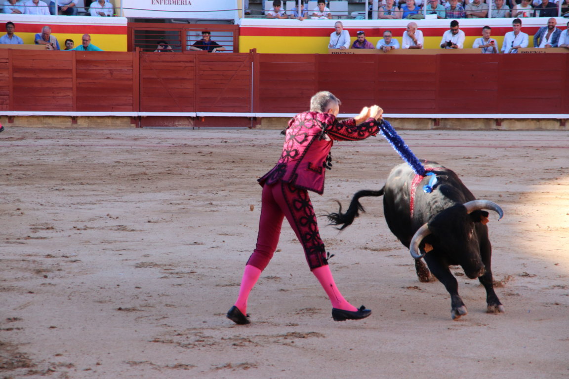 Torero en traje de luces lidiando un toro en la plaza de toros.