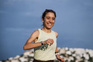 Sara García corriendo con una sonrisa en un paisaje despejado