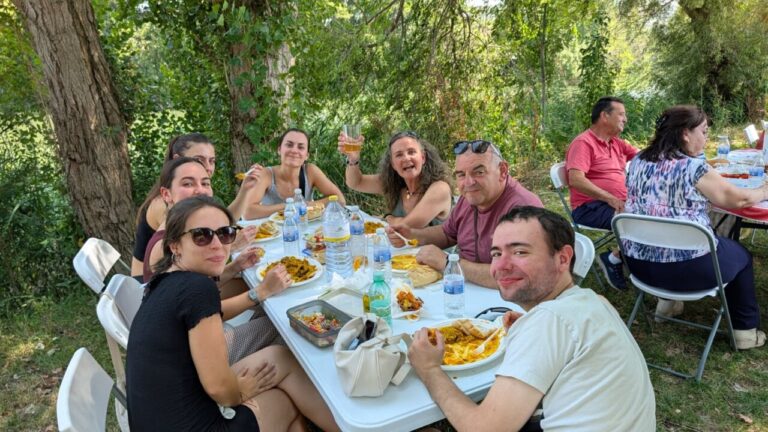 Grupo de personas disfrutando de una comida al aire libre junto al río