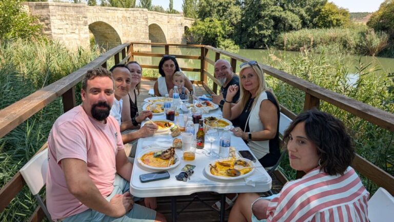 Grupo de personas disfrutando de una paellada junto al río Carrión en Husillos