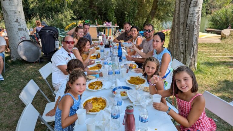 Grupo de personas disfrutando de una paellada junto al río Carrión en Husillos