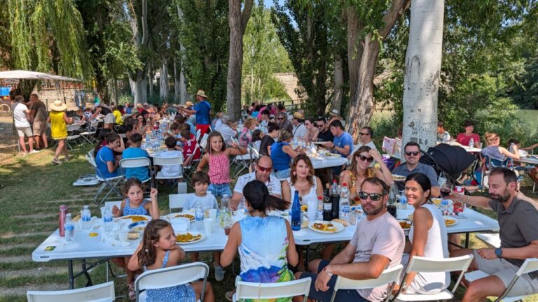 Grupo de personas disfrutando de una paellada junto al río Carrión en Husillos