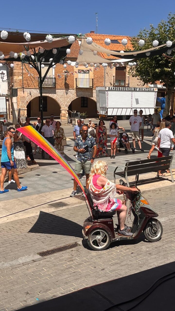 Persona en un scooter decorado con una bandera multicolor en un festival