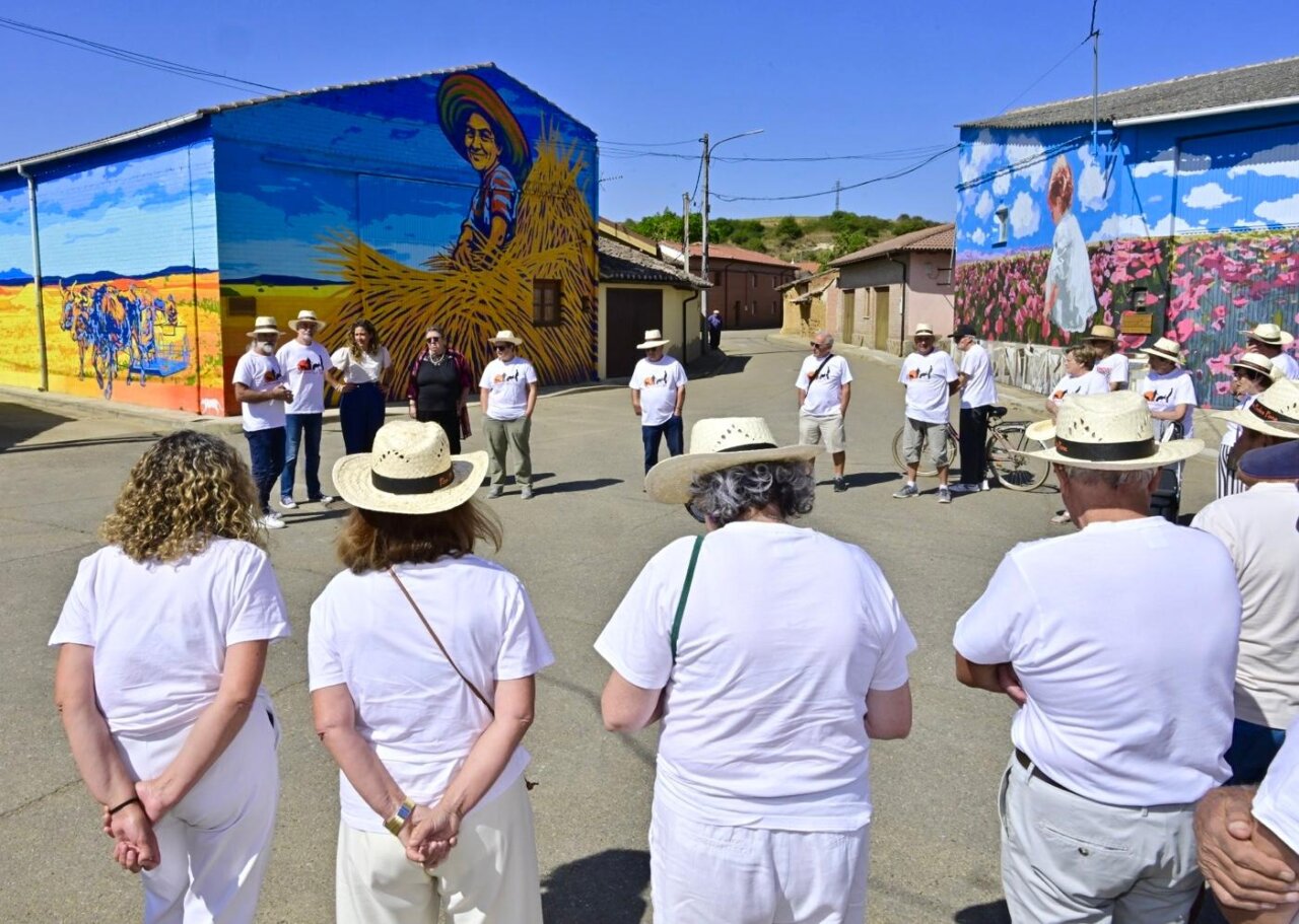 Grupo de personas frente a un mural colorido en Polvorosa de Valdavia