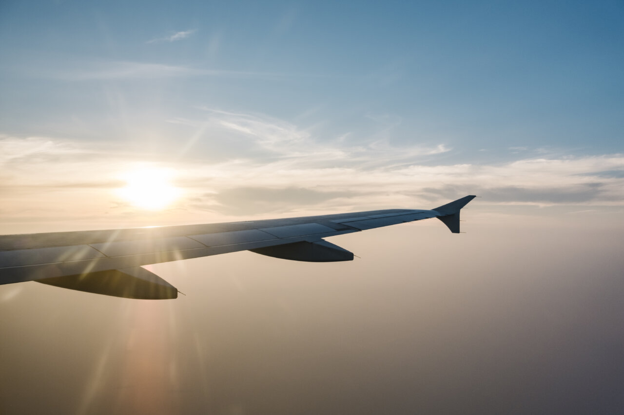 Vista del ala de un avión durante un atardecer en el cielo azul