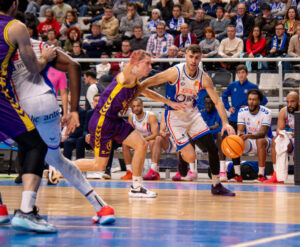 Jugador de baloncesto en acción durante un partido con la afición al fondo