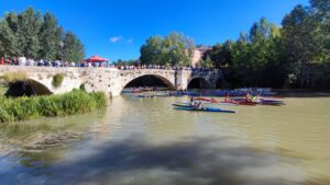 Competencia de piragüismo en el río Carrión con palistas y un puente