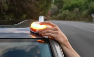 Mano colocando una baliza de emergencia en un vehículo en la carretera
