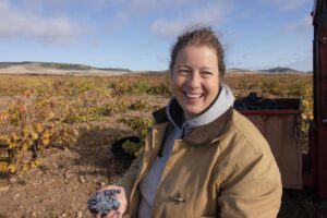 Mujer sonriente sosteniendo uvas en un viñedo de Bodega Remigio Salas
