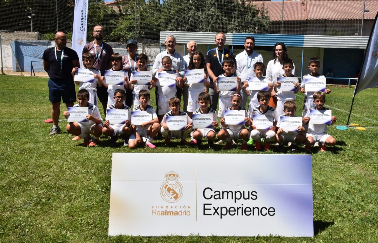 Grupo de niños con camisetas del Real Madrid sosteniendo diplomas en un campus de fútbol