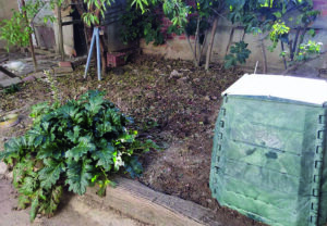 Compostero doméstico en un jardín con hojas y plantas