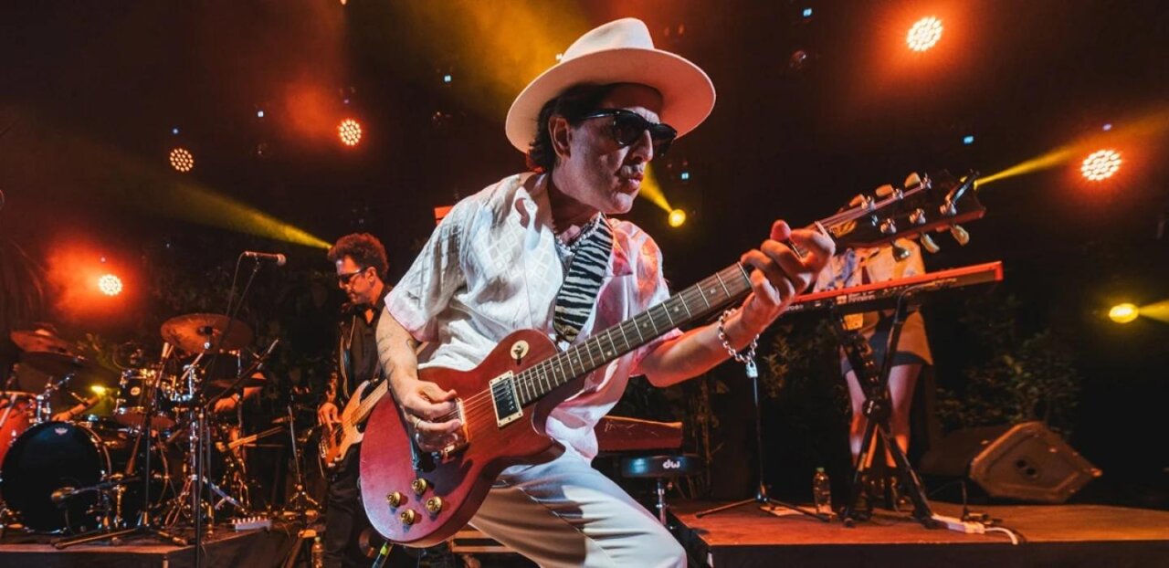 Coti tocando la guitarra en un concierto con luces de fondo