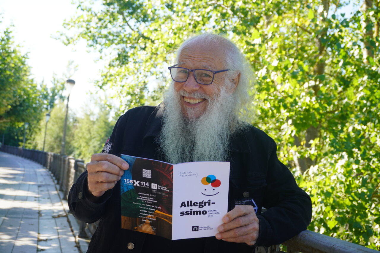 Dimas González sonriente sosteniendo un folleto de Allegríssimo en un parque.