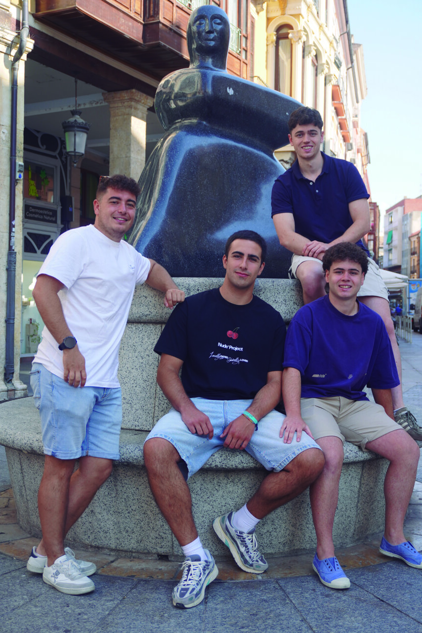 Cuatro jóvenes posando junto a una escultura en Cascón de la Nava