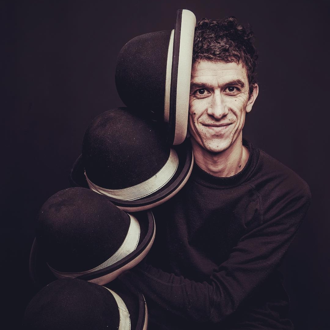 Retrato de Enrique Méndez, artista de circo contemporáneo con sombreros.