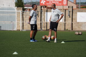 Dos entrenadores de fútbol conversando en el campo durante la pretemporada