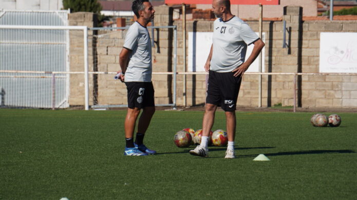 Dos entrenadores de fútbol conversando en el campo durante la pretemporada