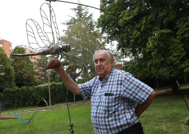 Hombre sosteniendo una escultura de insecto en un parque.