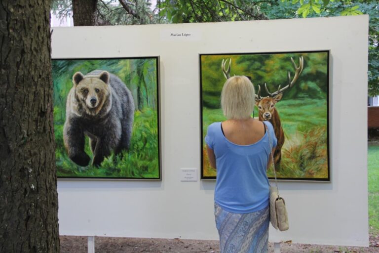 Mujer observando pinturas de un oso y un ciervo en una exposición de arte
